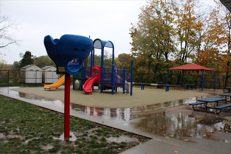 Empty outdoor playground with slides, climbing structures, and picnic tables