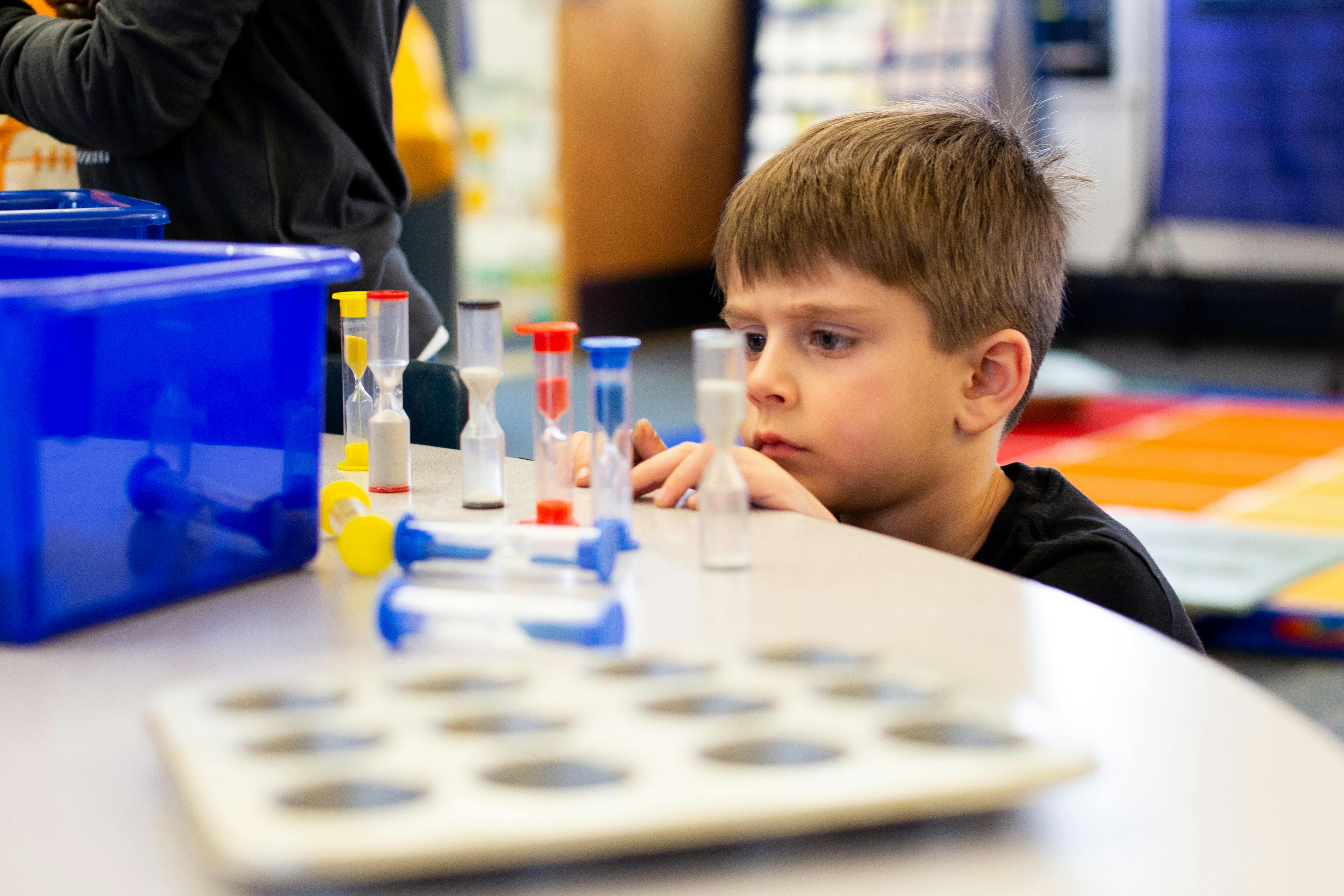Child looking at small hourglasses on a table