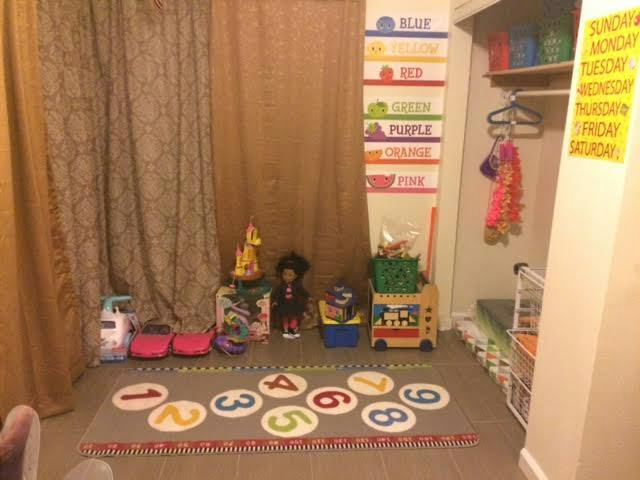 Playroom with number rug, toys, and color and day of the week charts