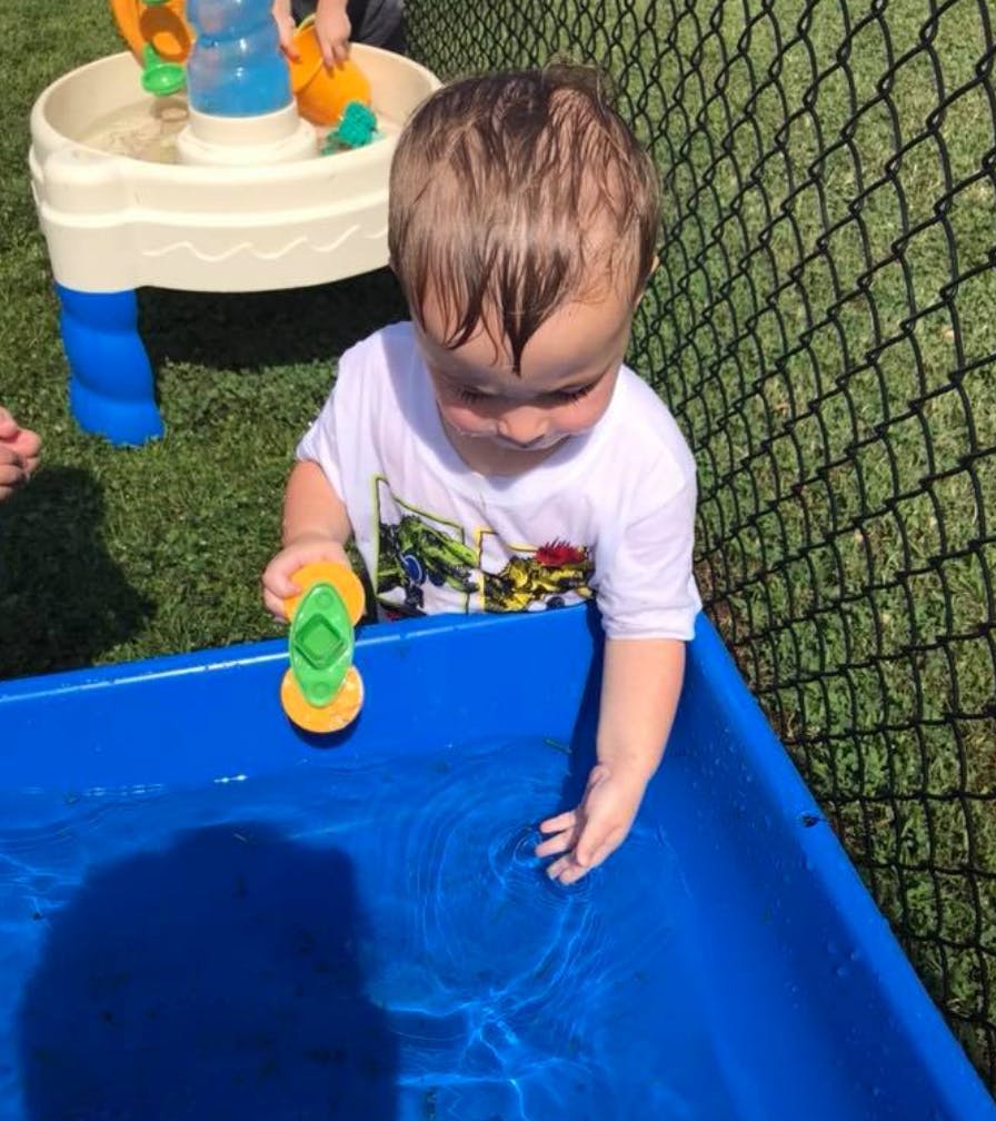 Child playing with a toy in a blue water table