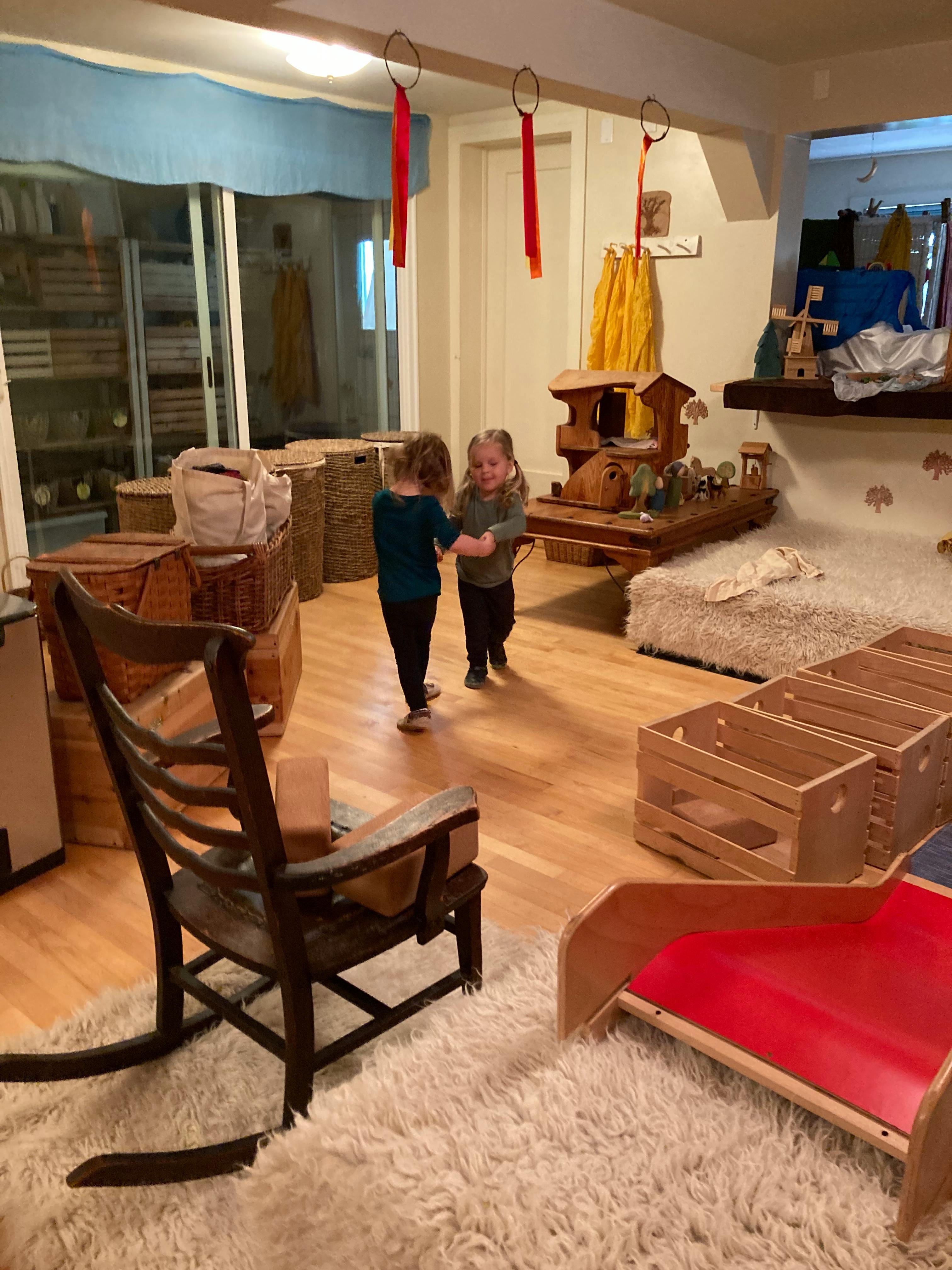 Two children holding hands in a room with wooden furniture