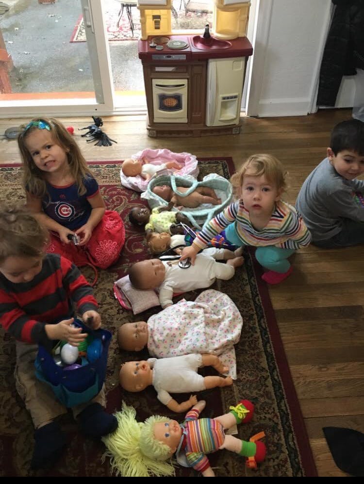 Children playing with baby dolls on a rug