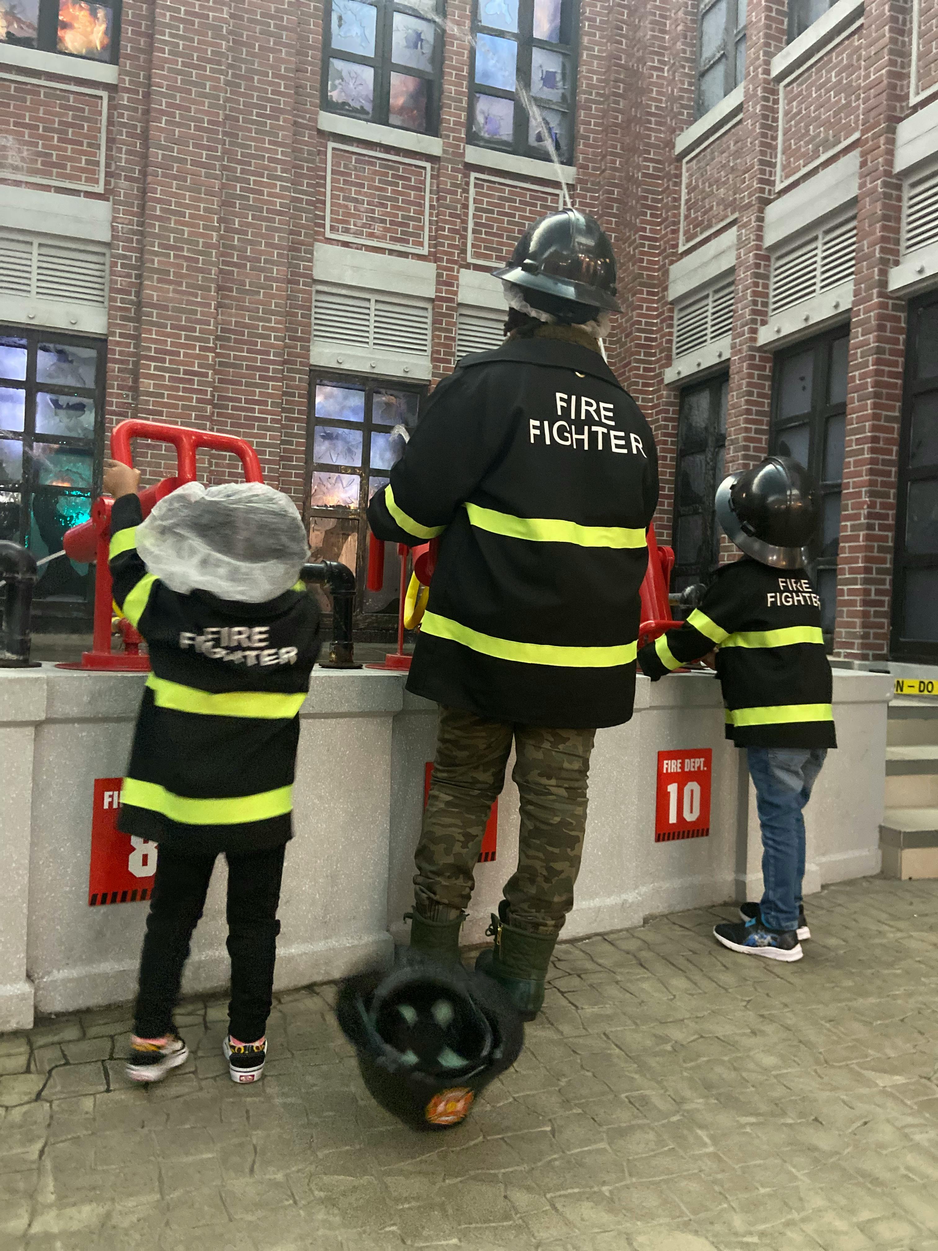 Three people in firefighter costumes with helmets
