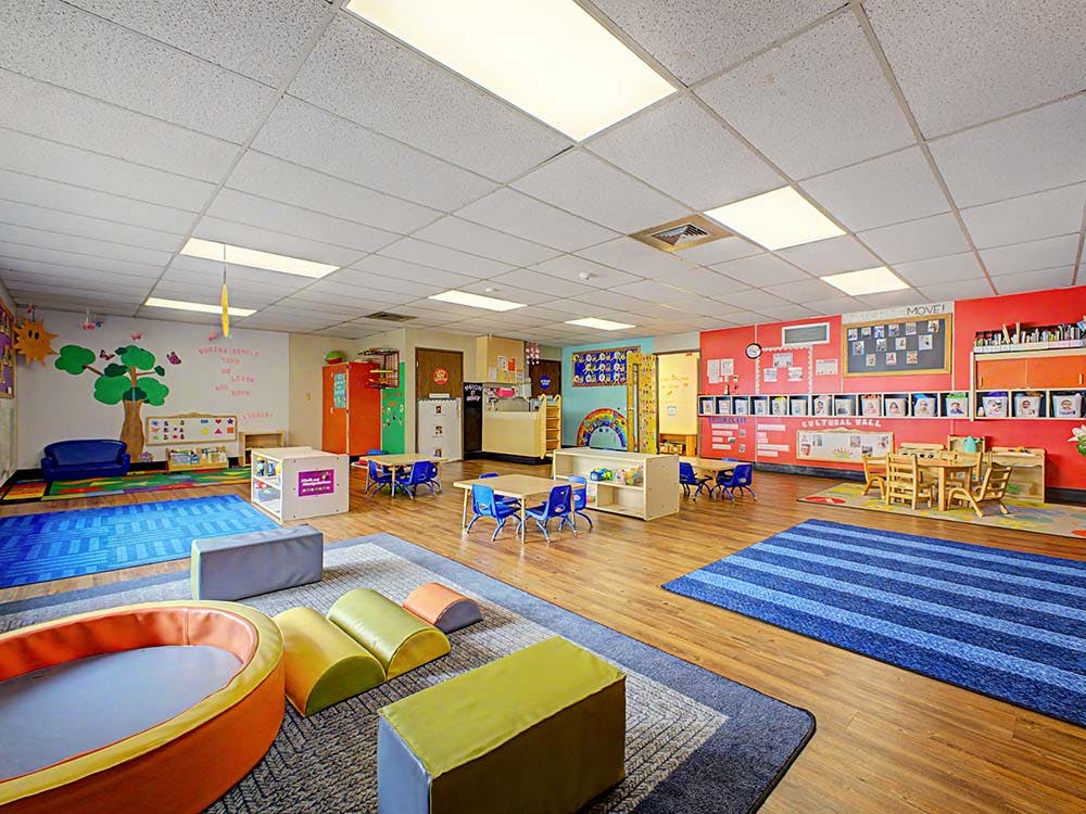 Empty colorful preschool classroom with small tables and chairs