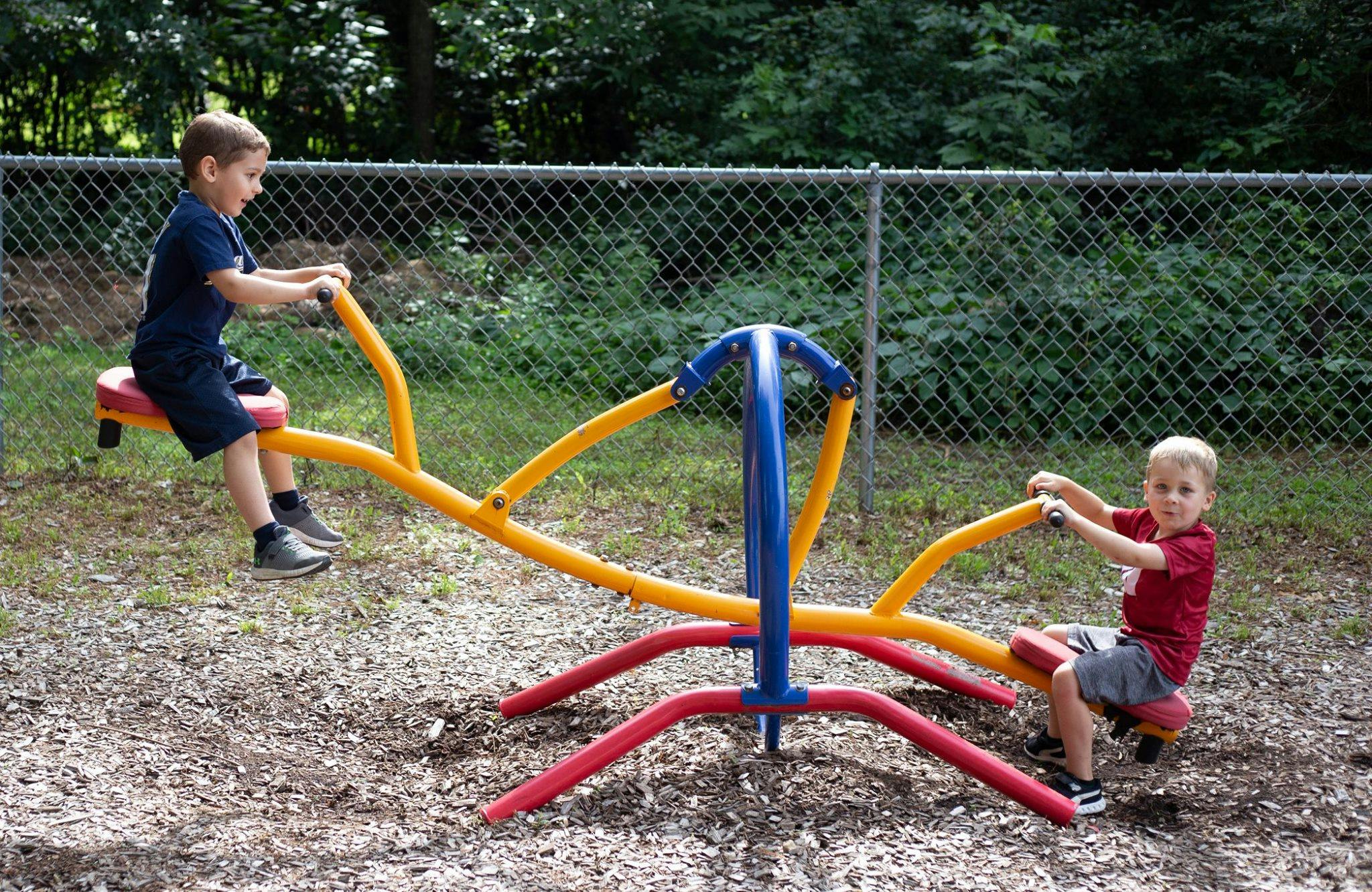 Two children playing on a seesaw in a playground