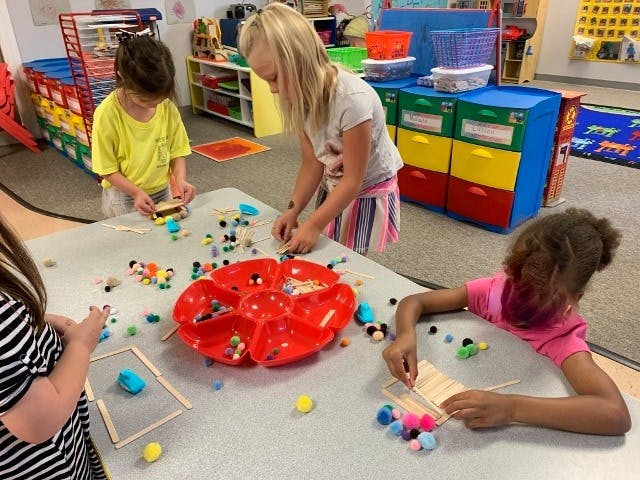 Children at a table doing crafts with craft supplies