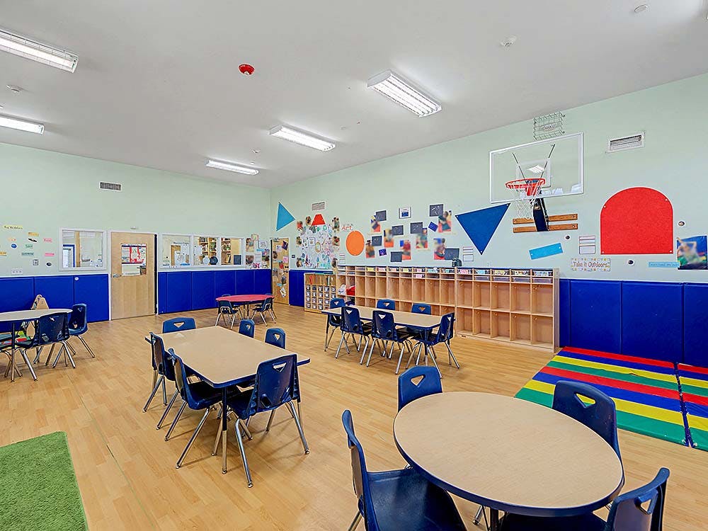 empty classroom with small tables, chairs, and shelves