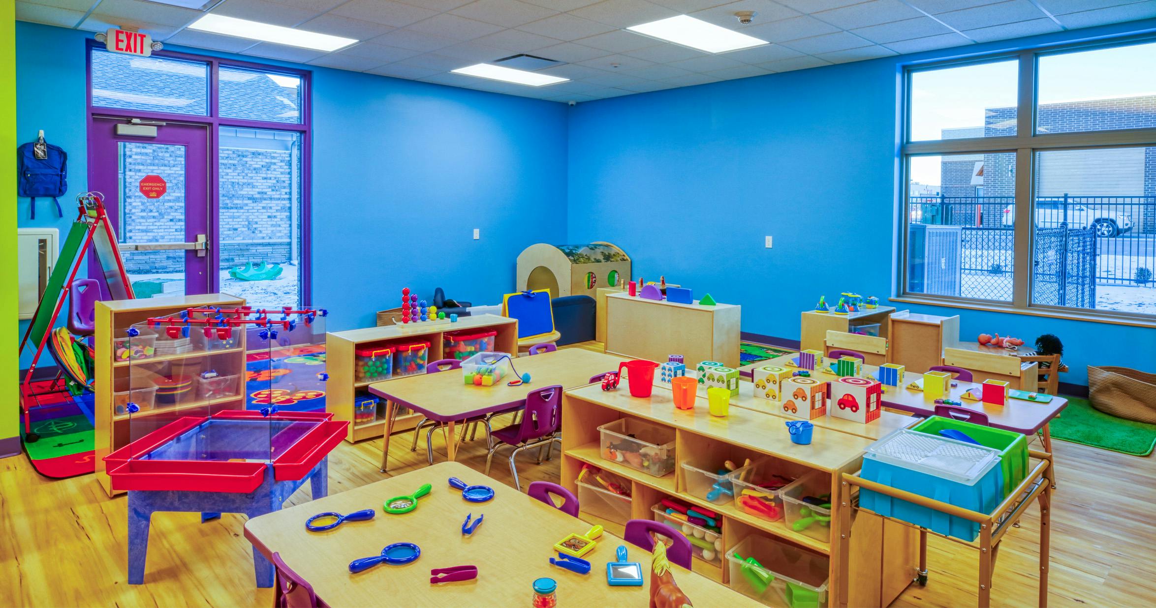 Classroom filled with small tables, chairs, toys, and learning materials