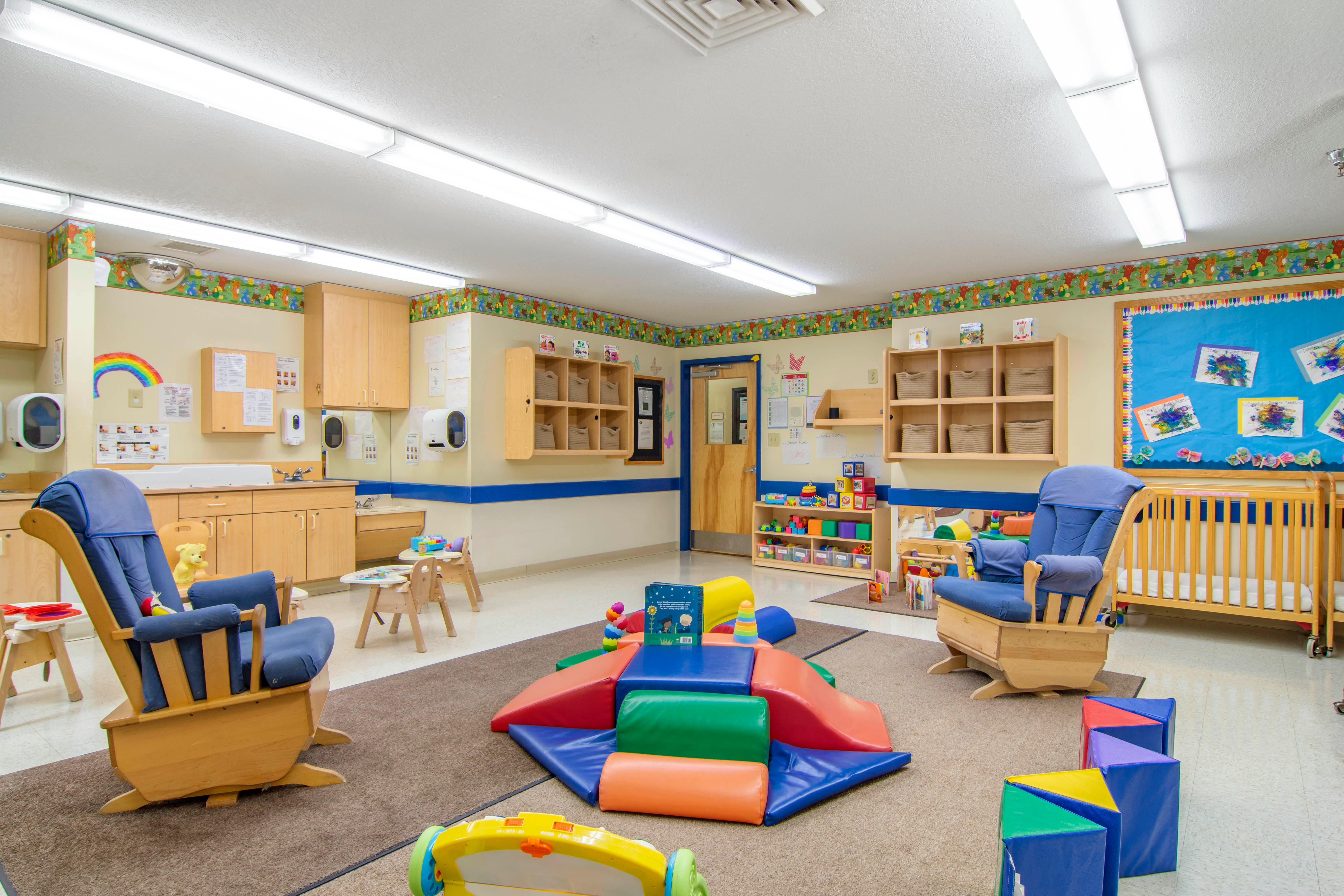 A colorful daycare or classroom with play mats and furniture