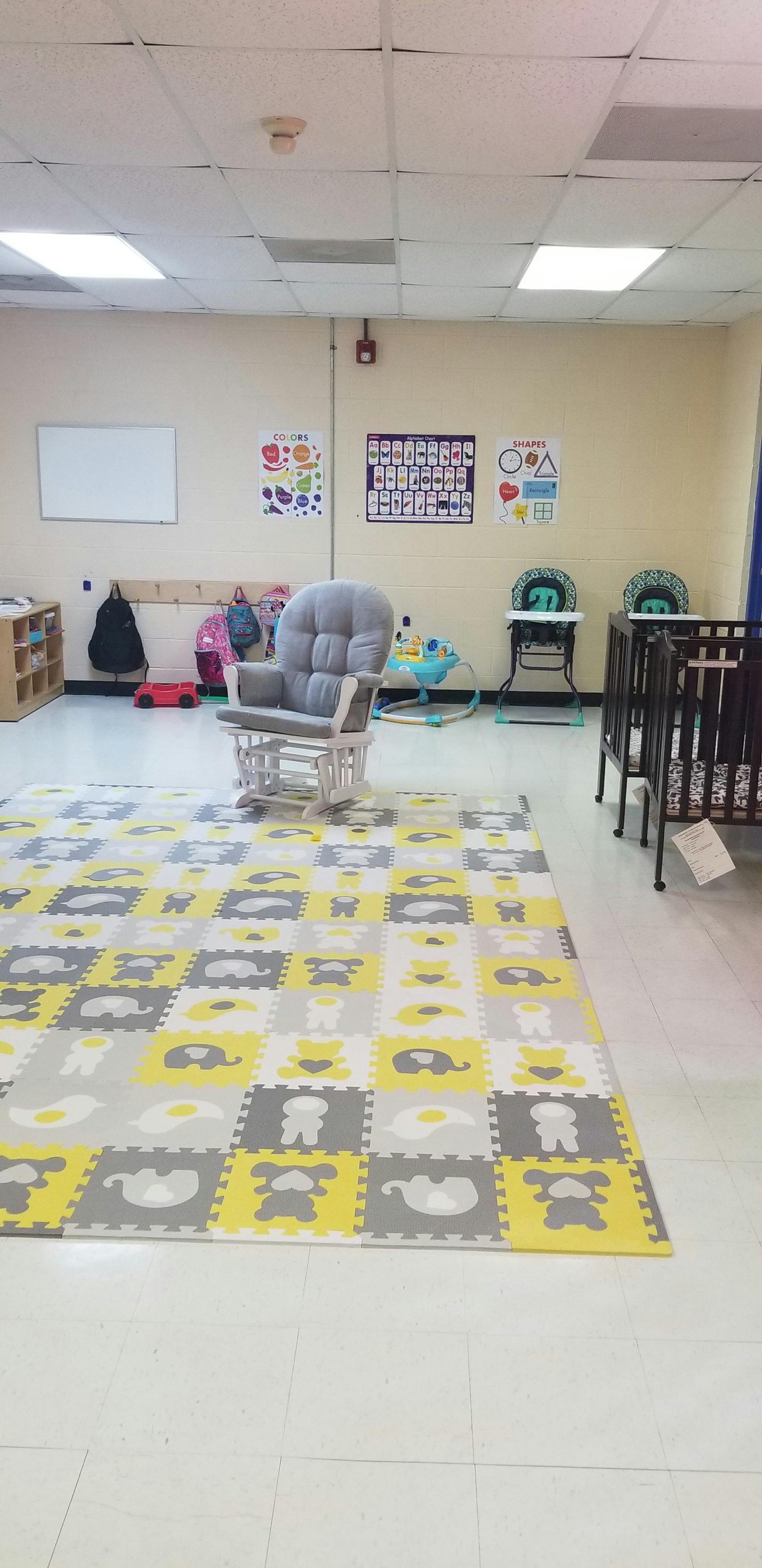 Nursery room with a rocking chair, play mat, and cribs
