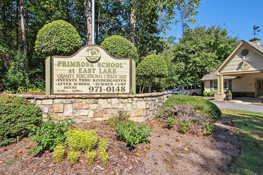 Primrose School at East Lake sign on a stone wall with green bushes