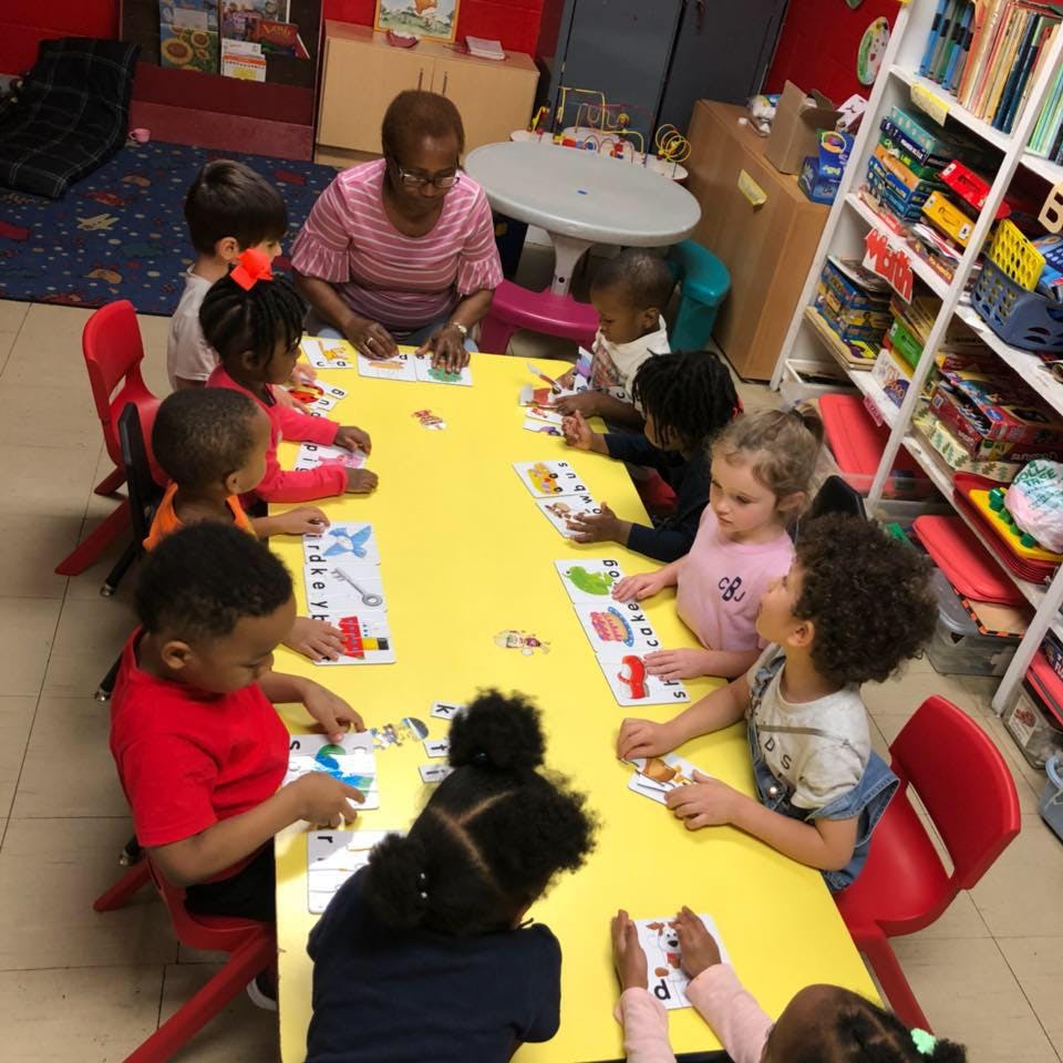 Person and children sitting at a table doing an activity