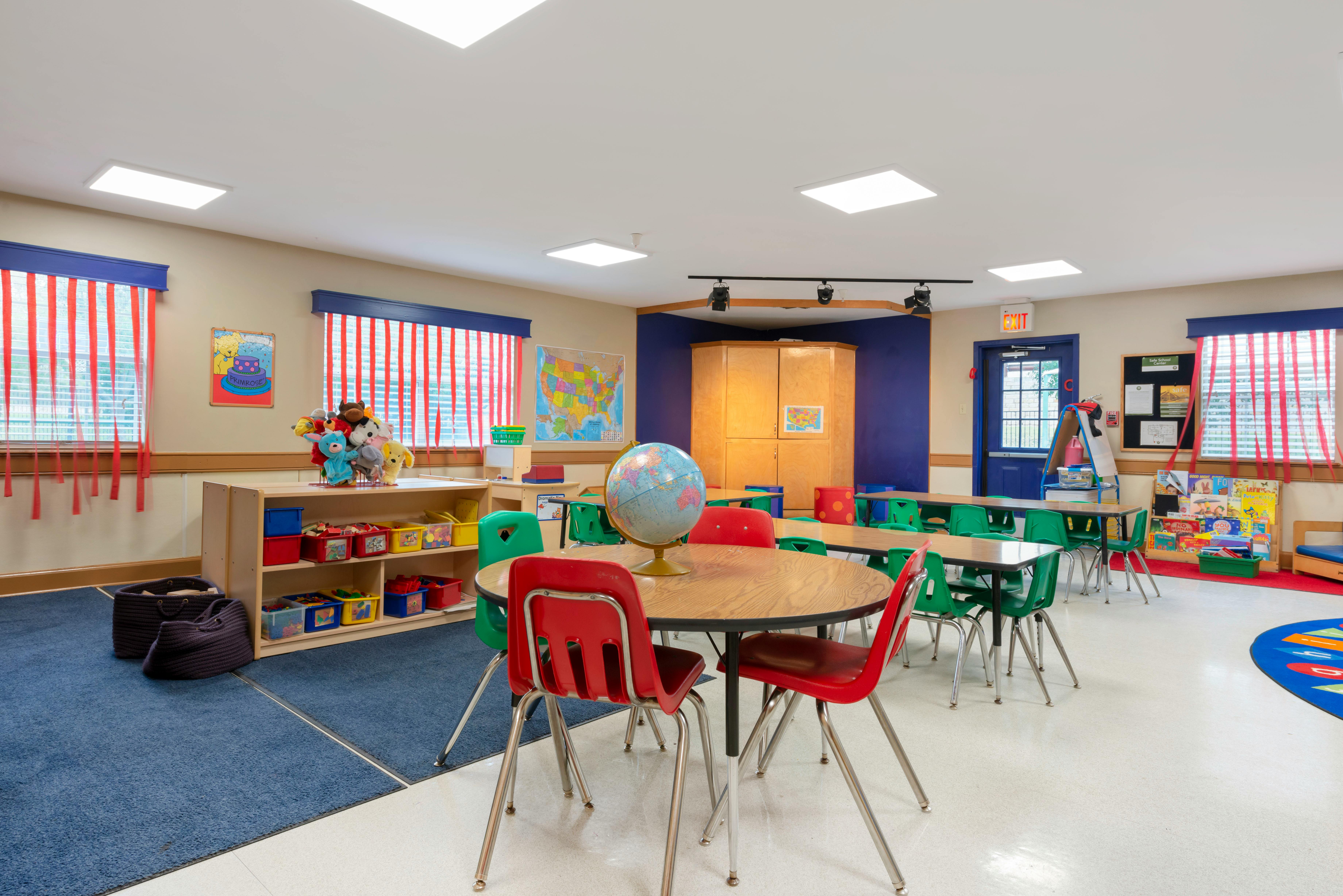 Classroom with child-sized tables and chairs, a globe, and toy shelves