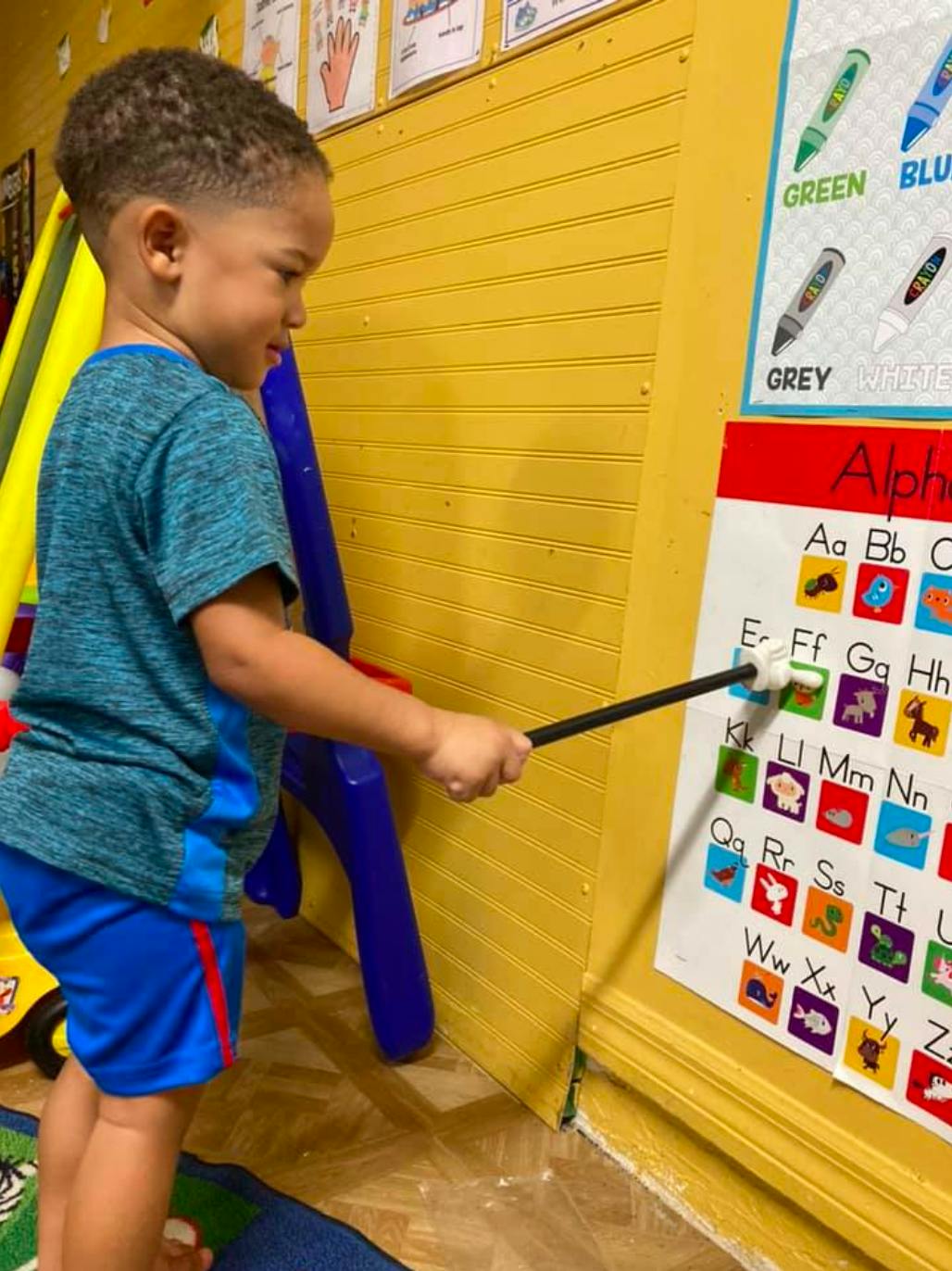 Child pointing to an alphabet chart with a pointer