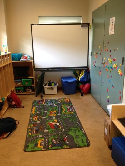 Classroom with a whiteboard, storage, and a play rug