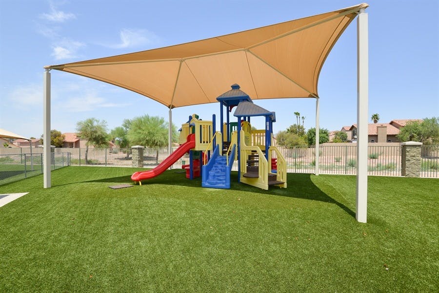 Playground with slides and climbing structures under a large shade canopy