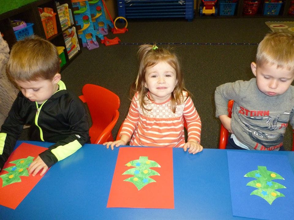 Three children at a table with paper crafts