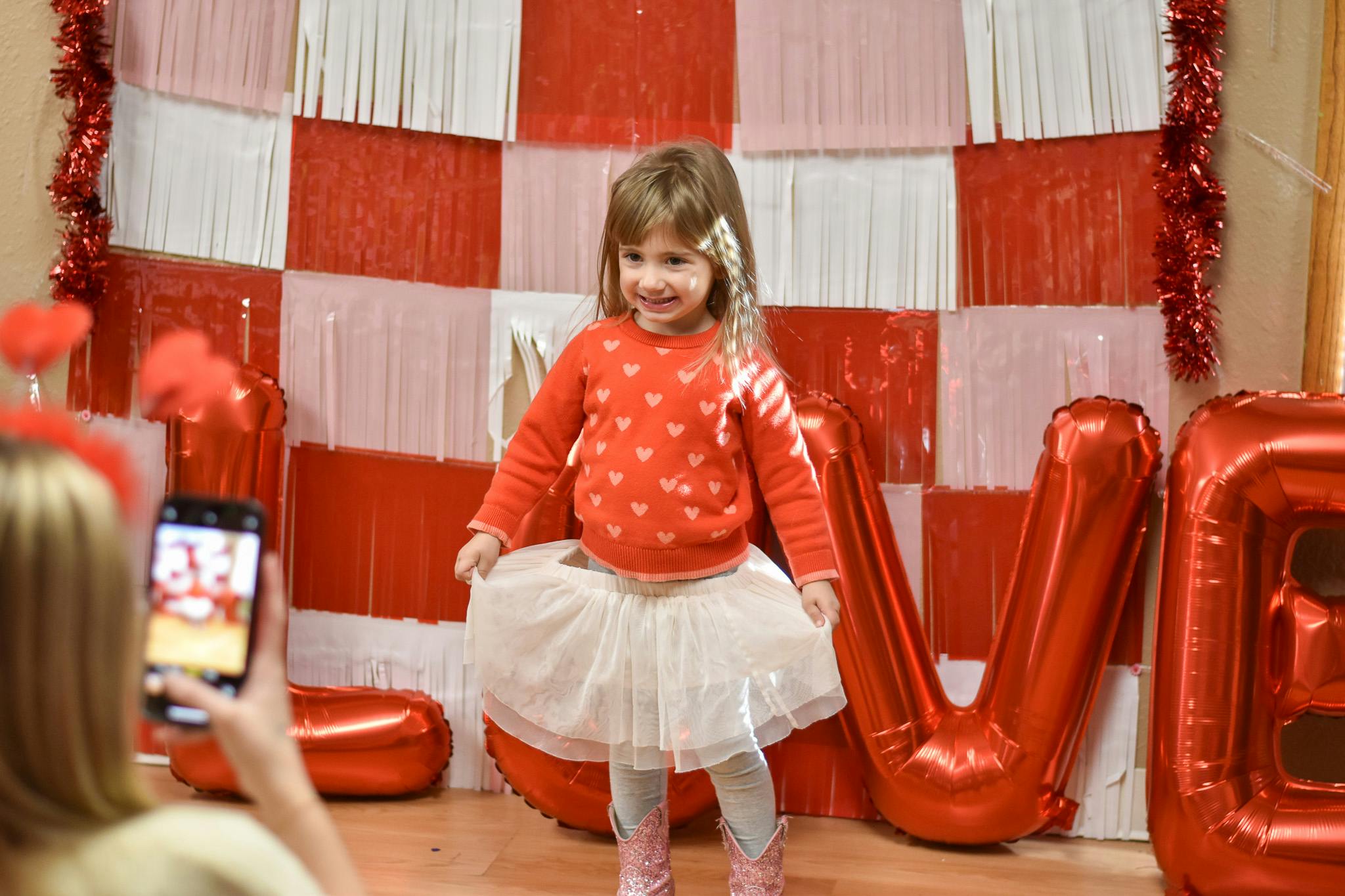 Child in heart sweater and tutu posing for a photo