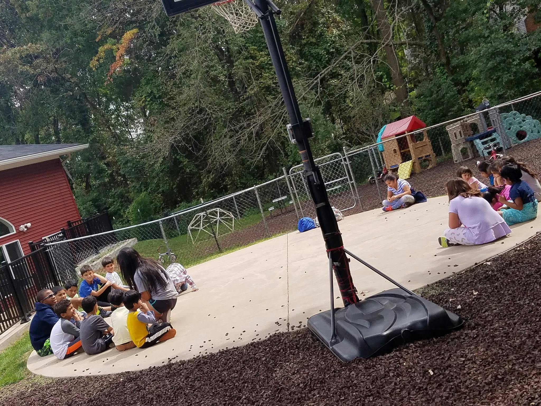 Children sitting on a paved area outdoors