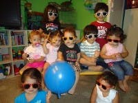Group of children wearing sunglasses, one child holding a blue balloon