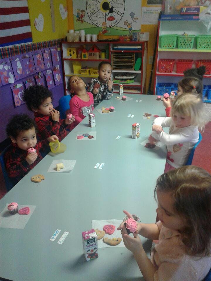 Children sitting at a table decorating cookies