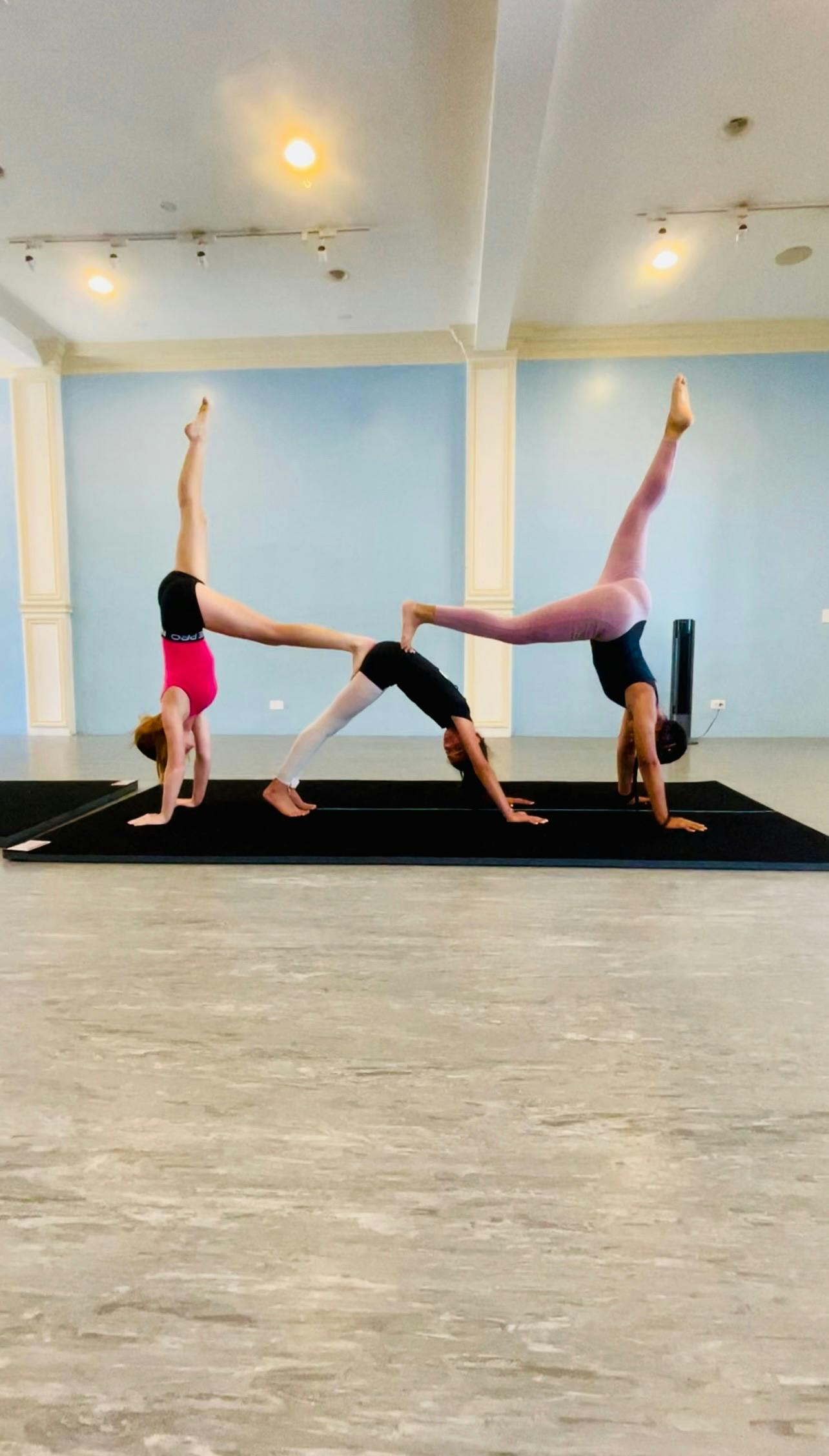 Three people in a yoga studio performing acroyoga poses