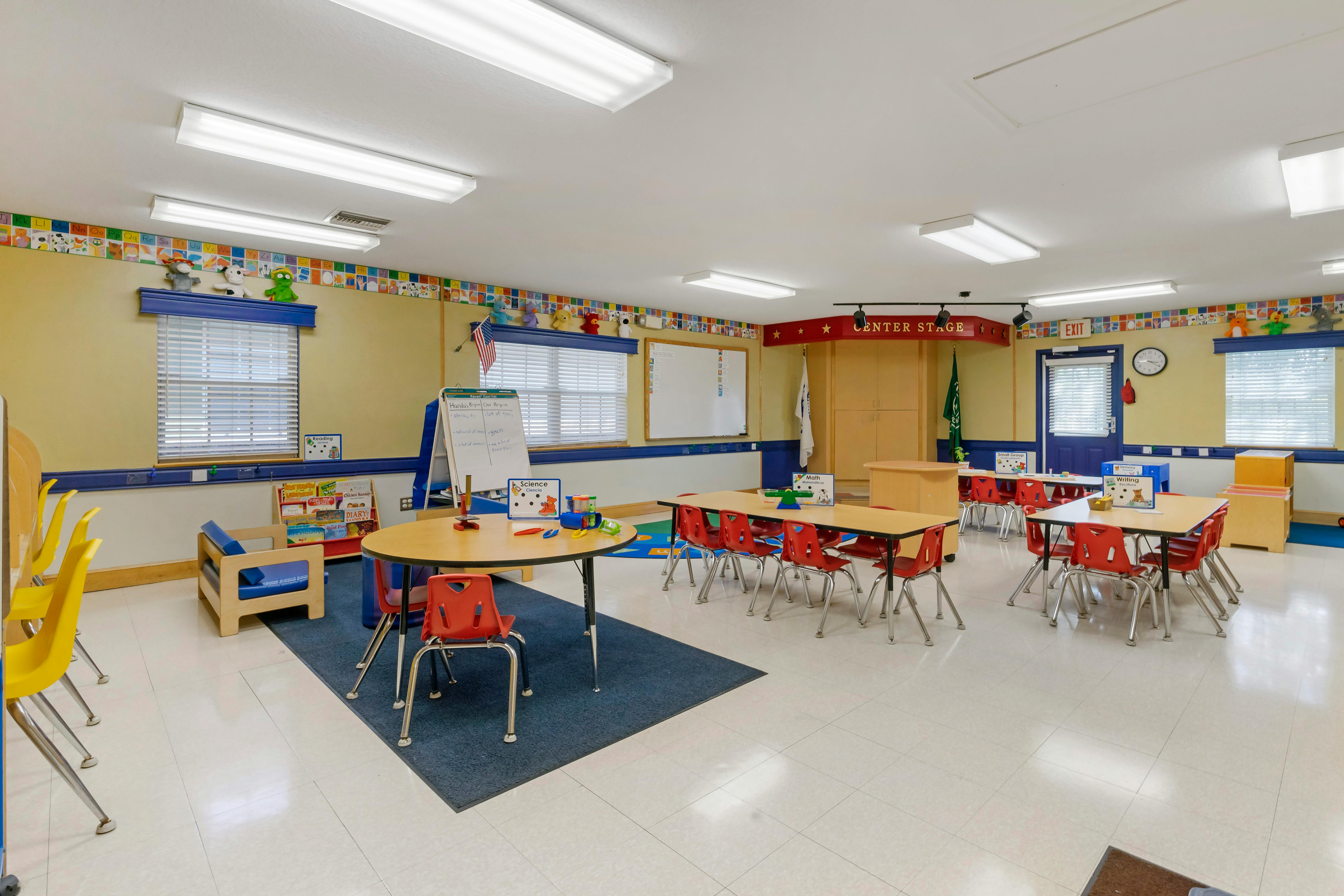 Classroom with small tables and chairs, whiteboards, and a "Center Stage" sign