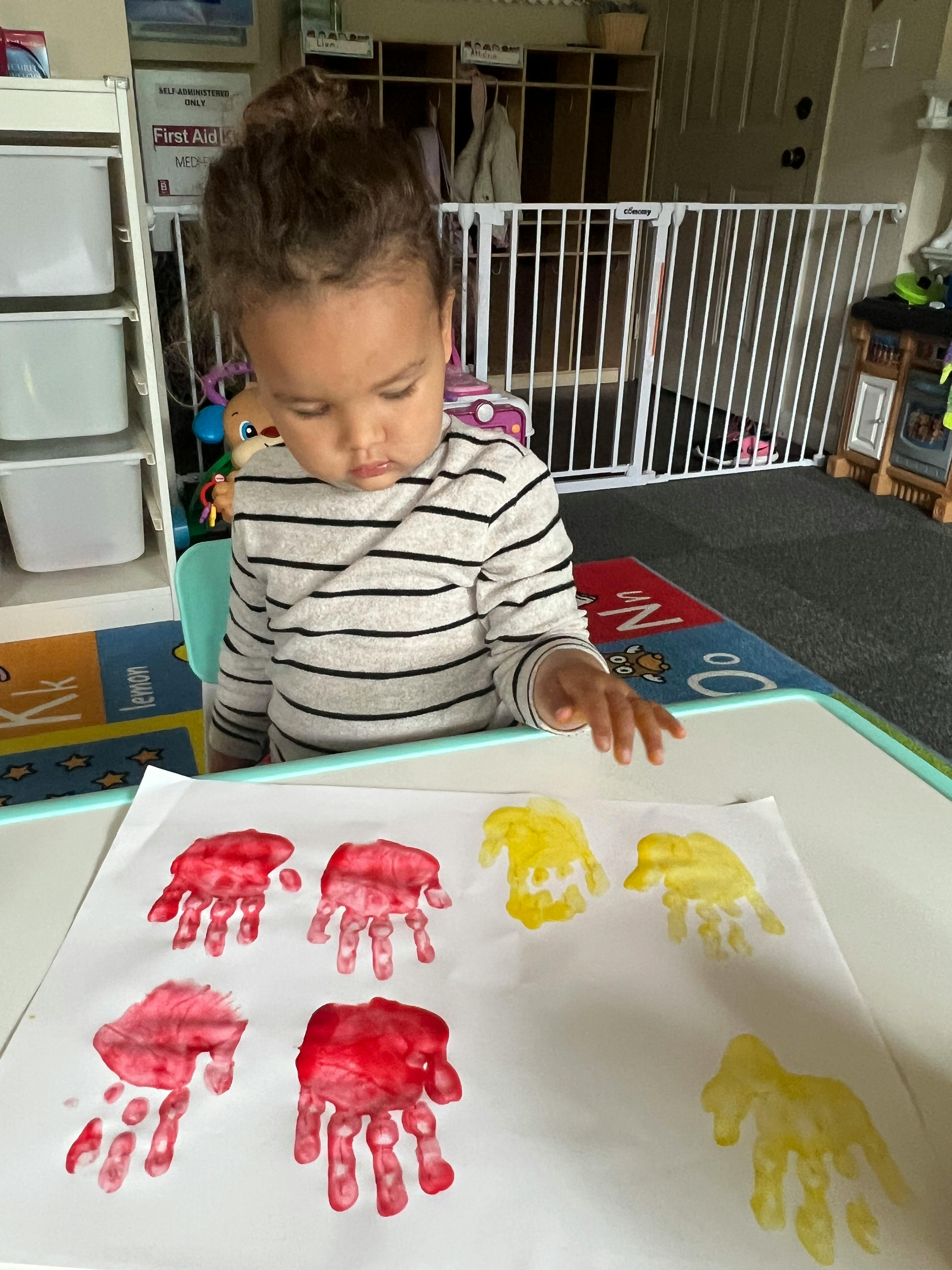 Child looking at handprints on paper