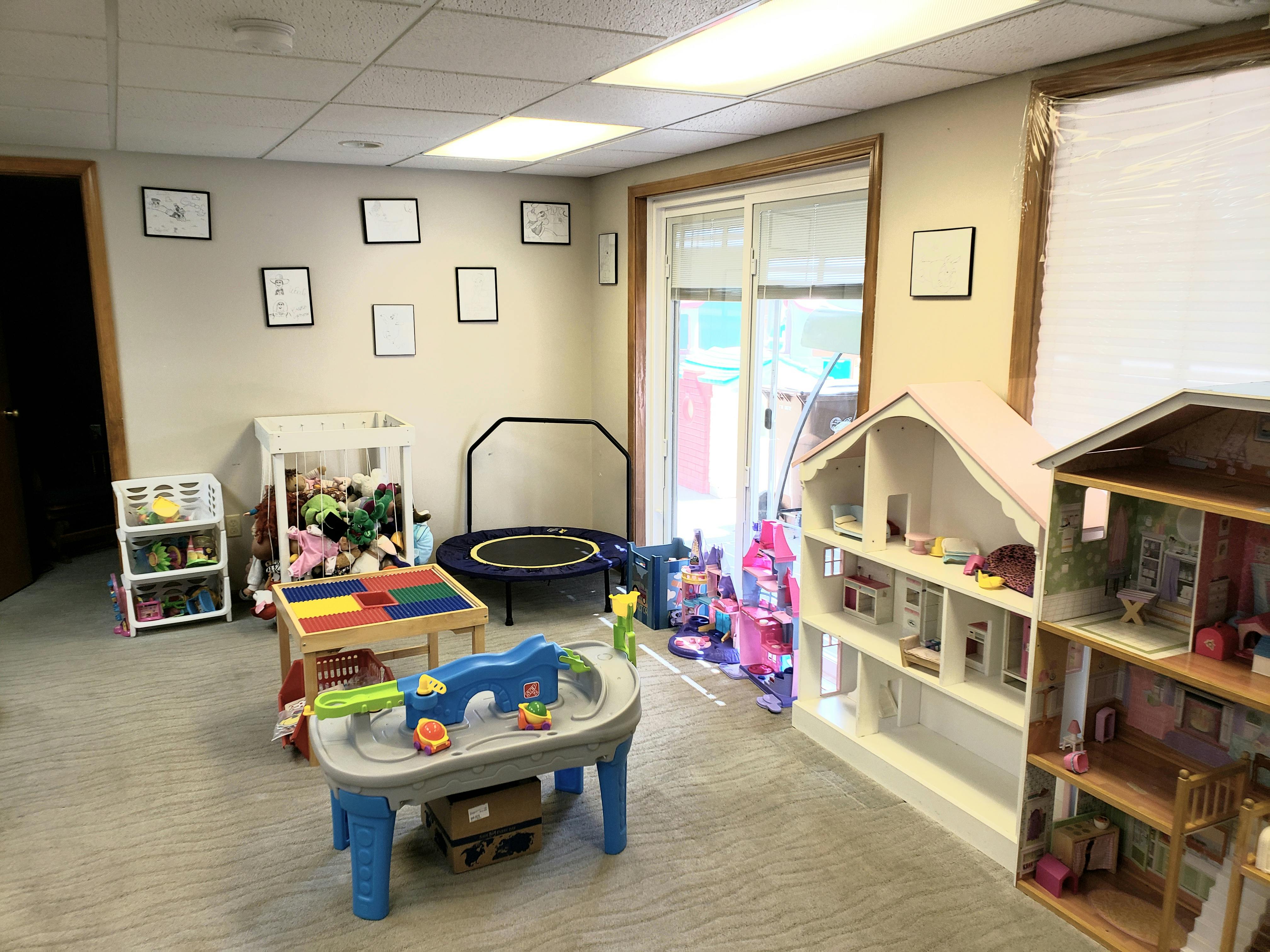 Playroom with various toys, including a trampoline, dollhouses, and play tables