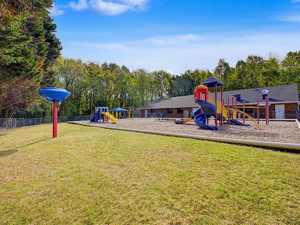 Playground equipment including slides, monkey bars, and swings on wood chips
