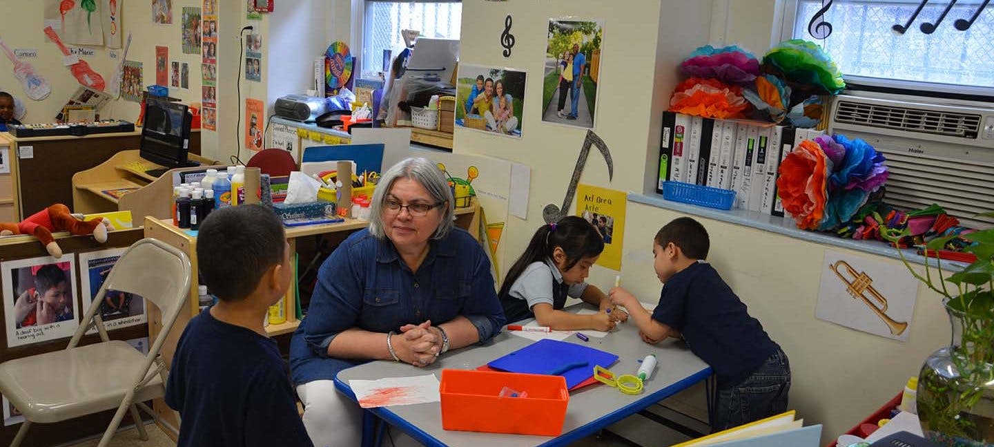 Adult and three children at a table in a classroom