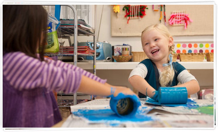 Two children painting with blue paint