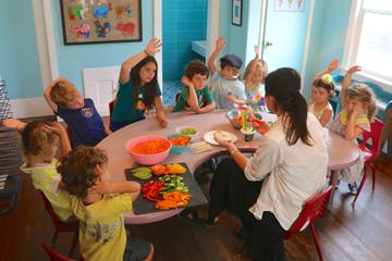 Adult and children at a table with vegetables