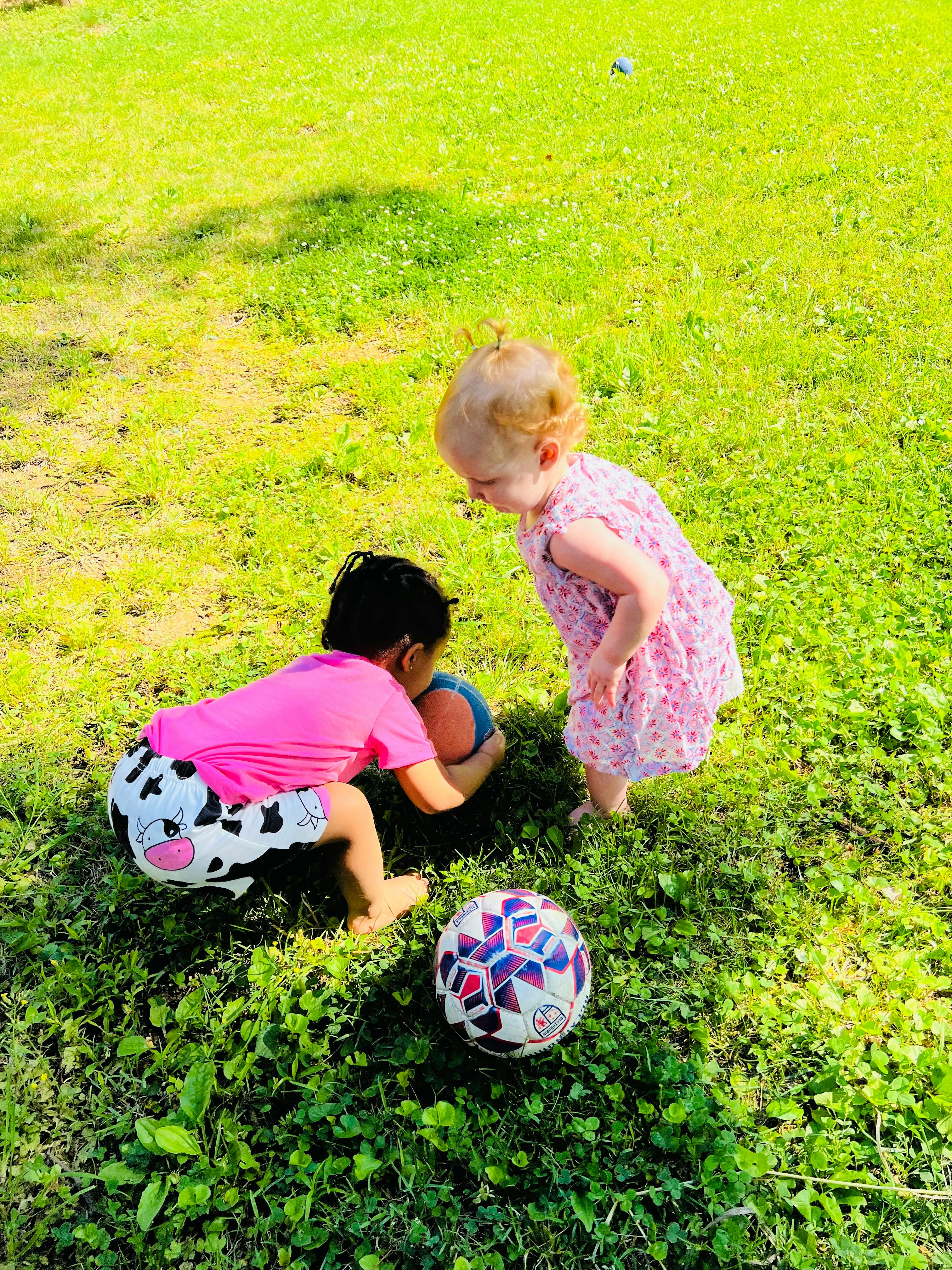 Two children playing with a ball on grass
