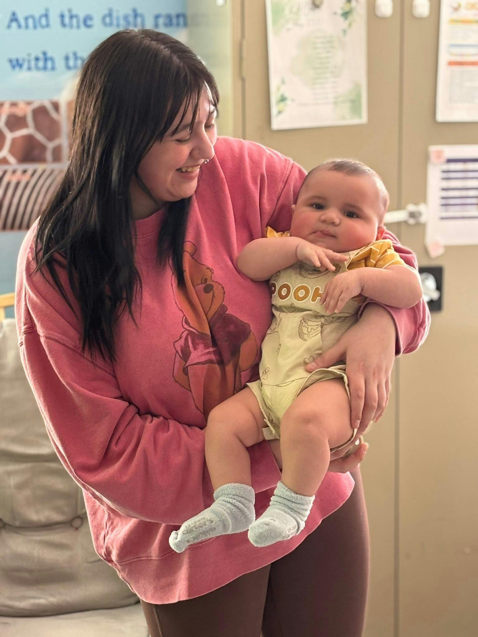 A person holding a child wearing a Pooh shirt