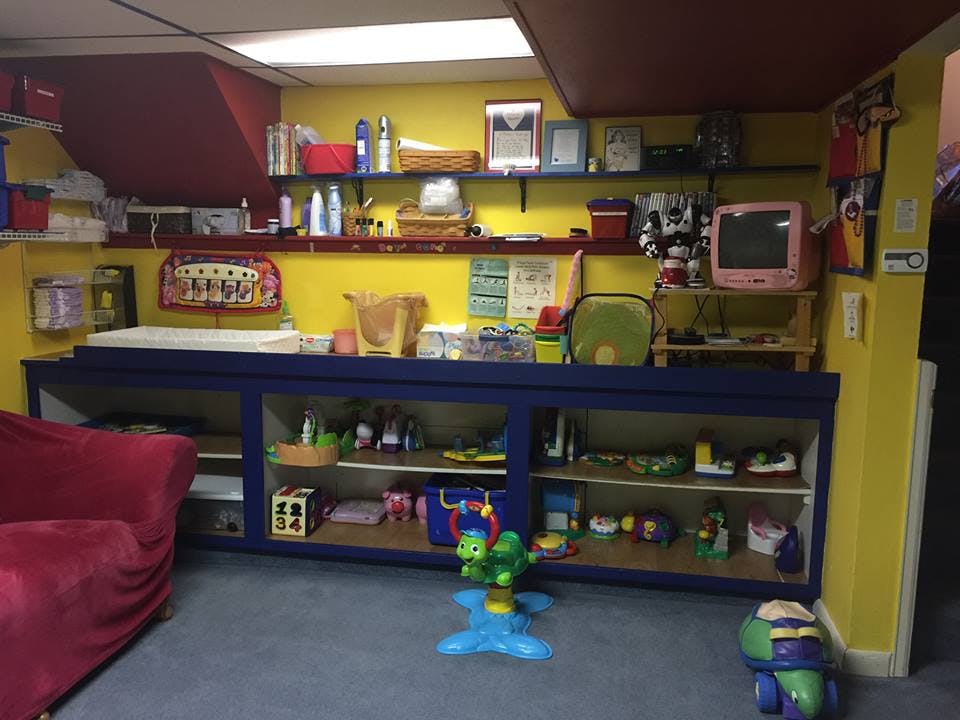 Room with shelves of items, a red couch, and toys on the floor