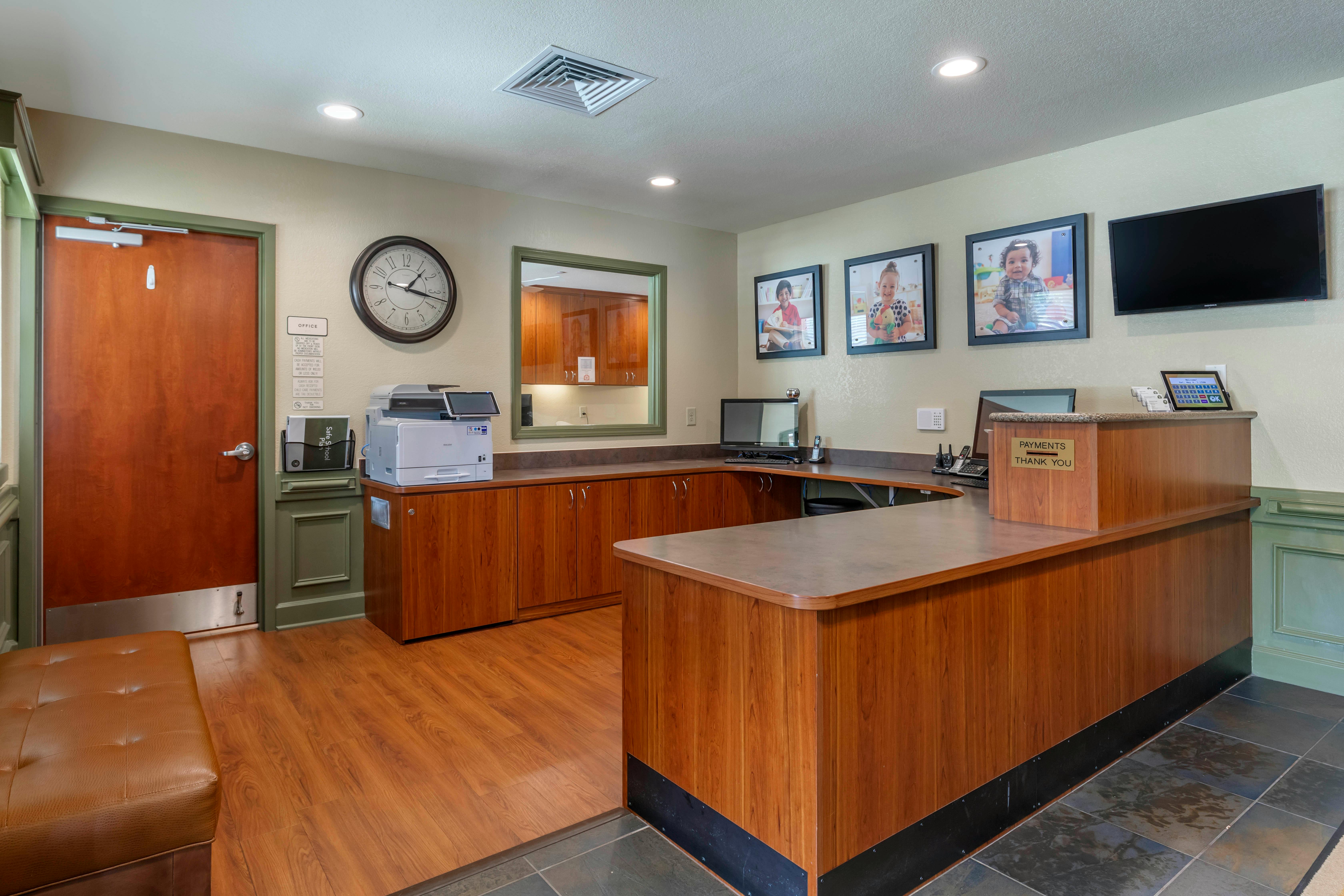 Reception desk with wood paneling, wall clock, and framed photos