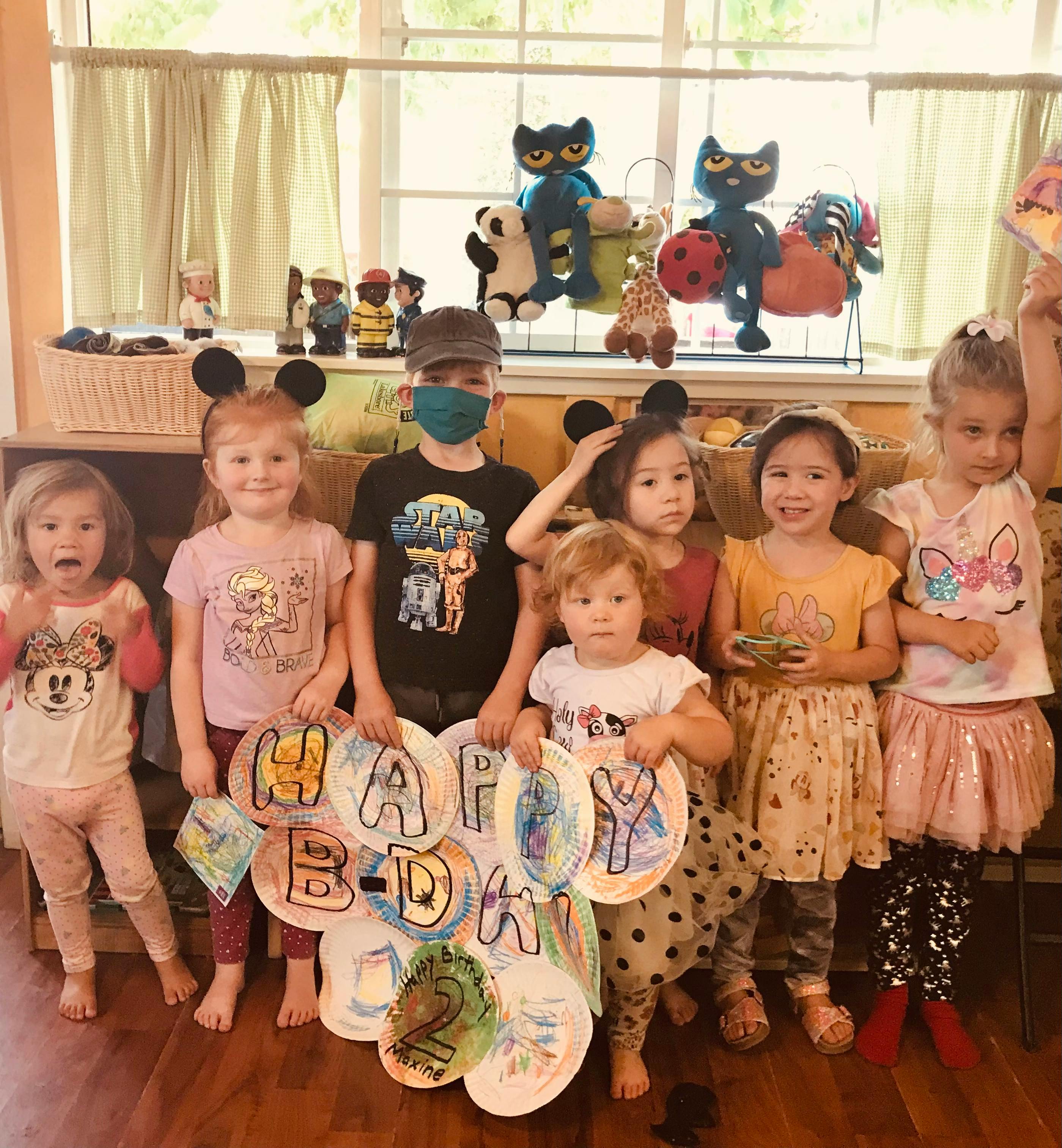 Group of children holding up paper plates that spell "Happy Birthday"