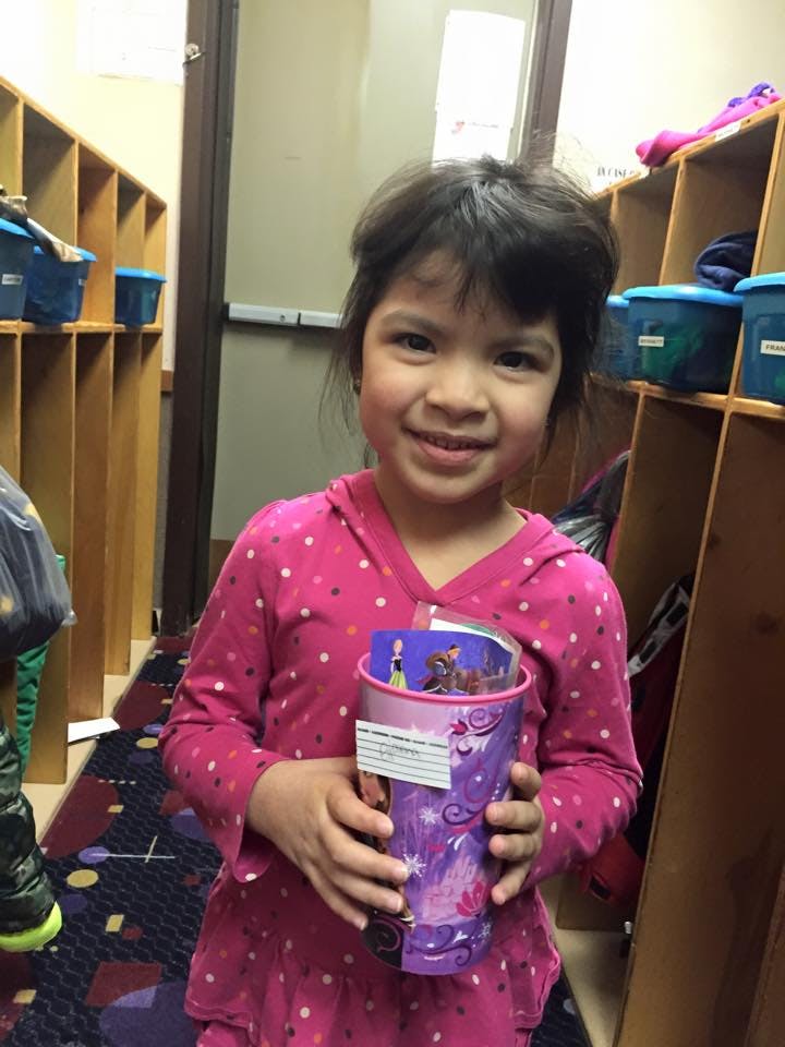 Child holding a purple cup with cards inside