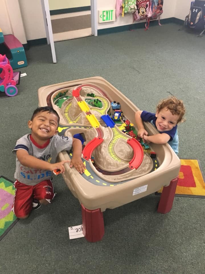 Two children playing with a toy car track table