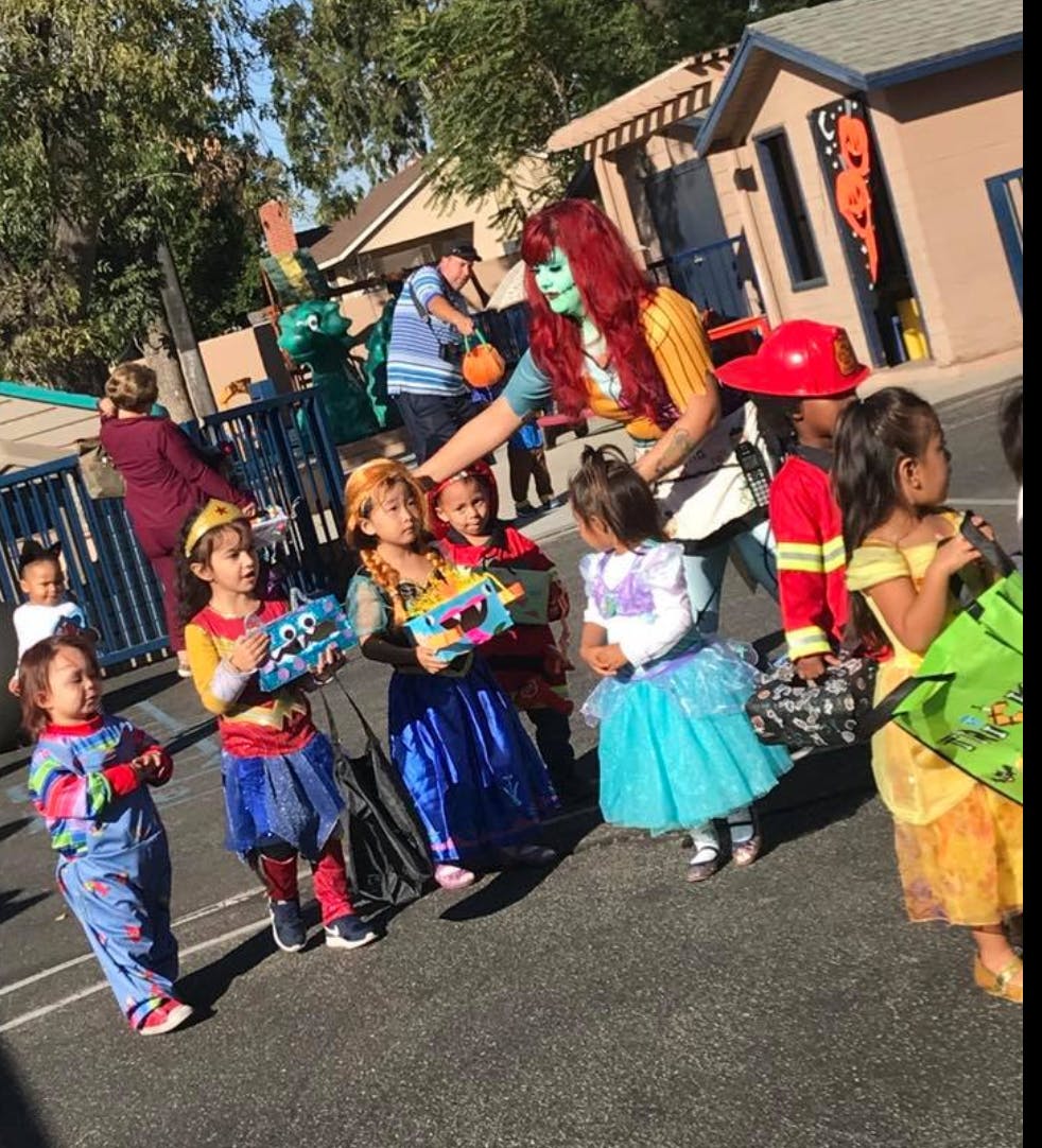 Person in costume with children in costumes holding treat bags