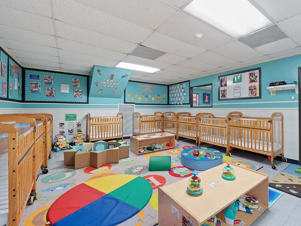 cribs in a brightly lit infant classroom
