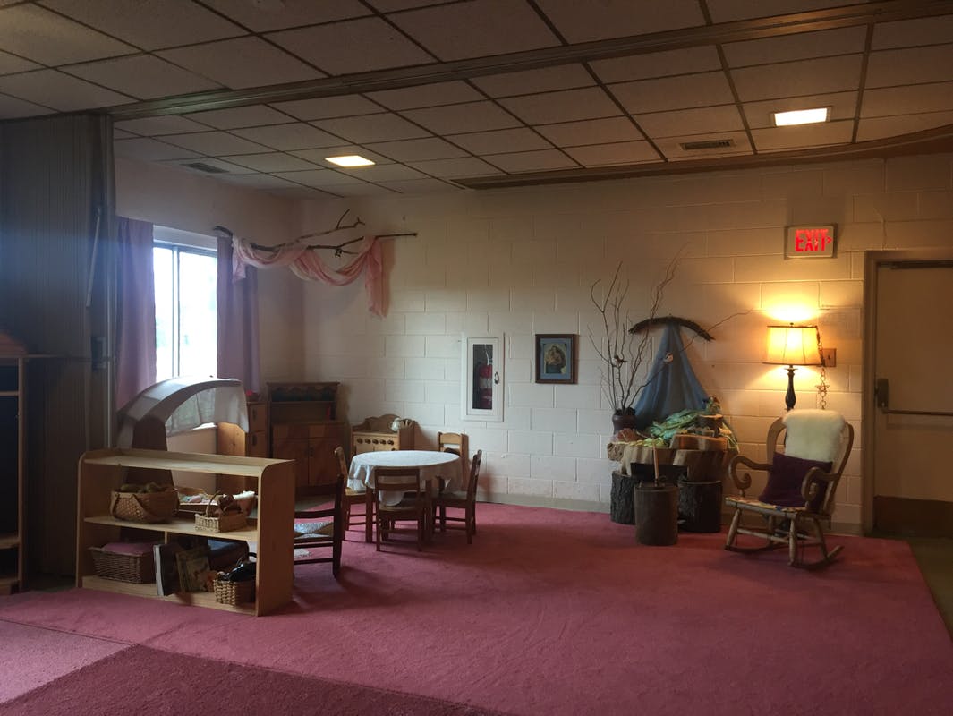 Room with red carpet, small table and chairs, and a rocking chair