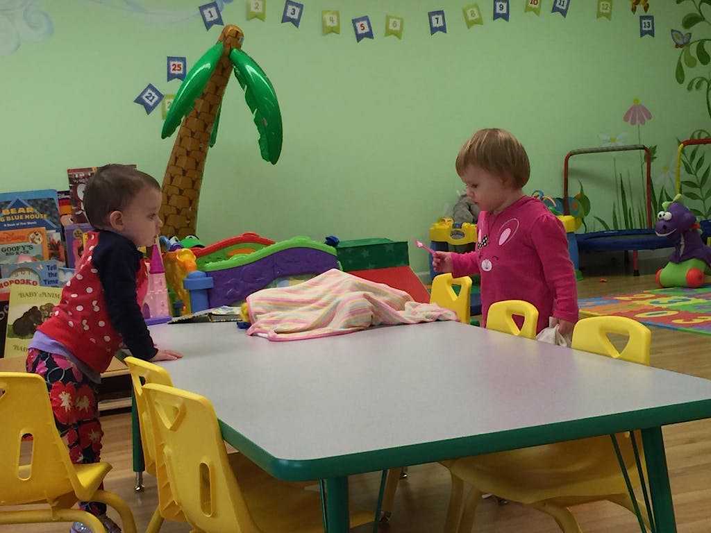 Two children standing at a table in a classroom