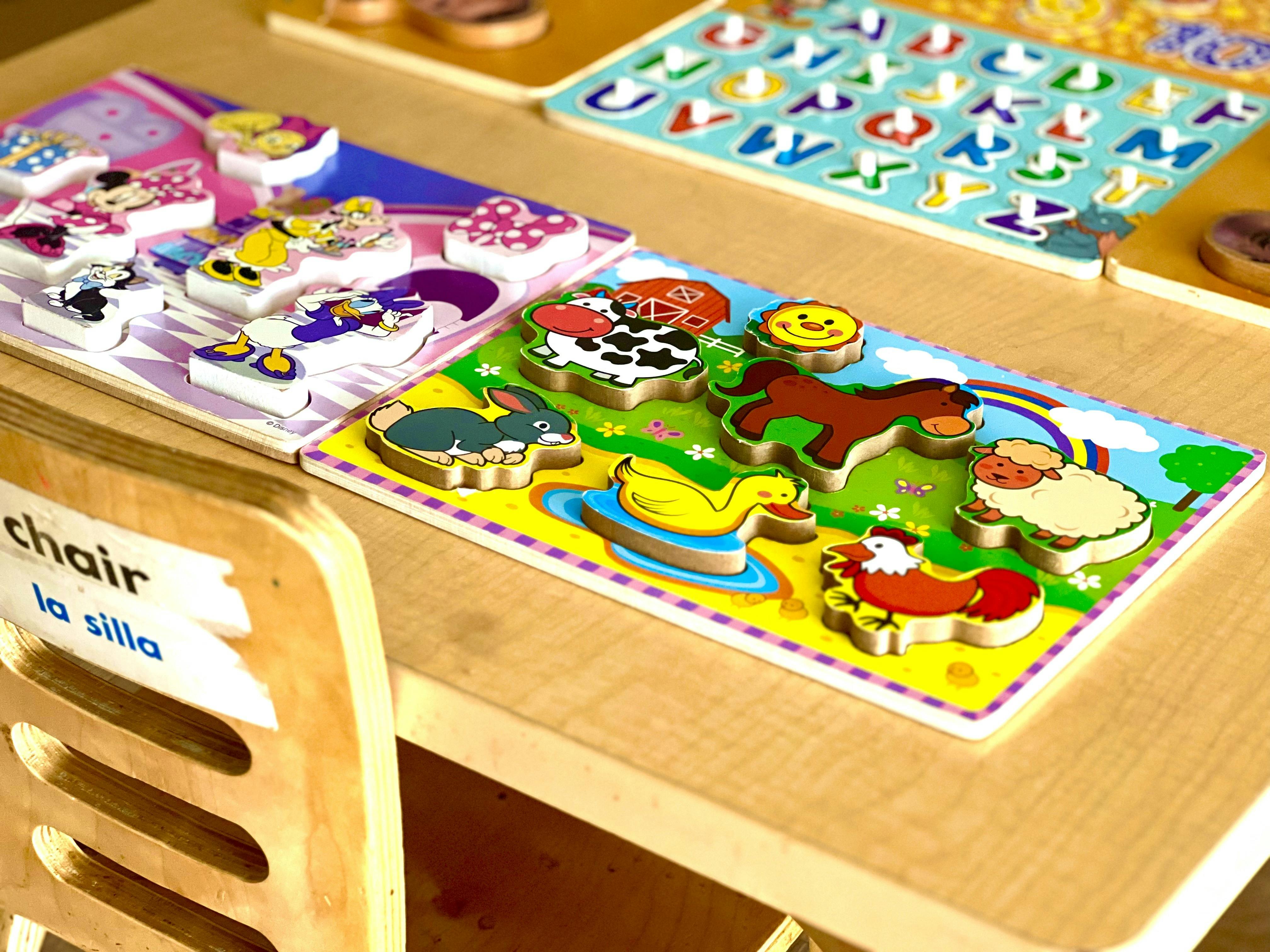 Wooden puzzles on a table, including Disney characters, farm animals, and alphabet letters