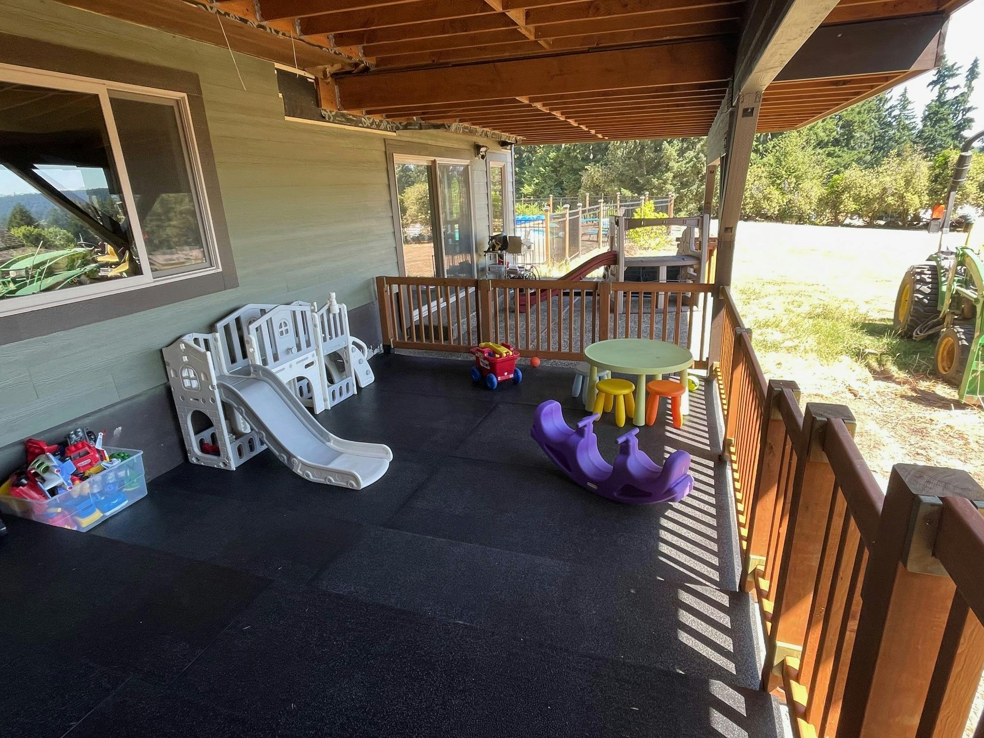 Play area on a porch with a slide, table, and purple rocker