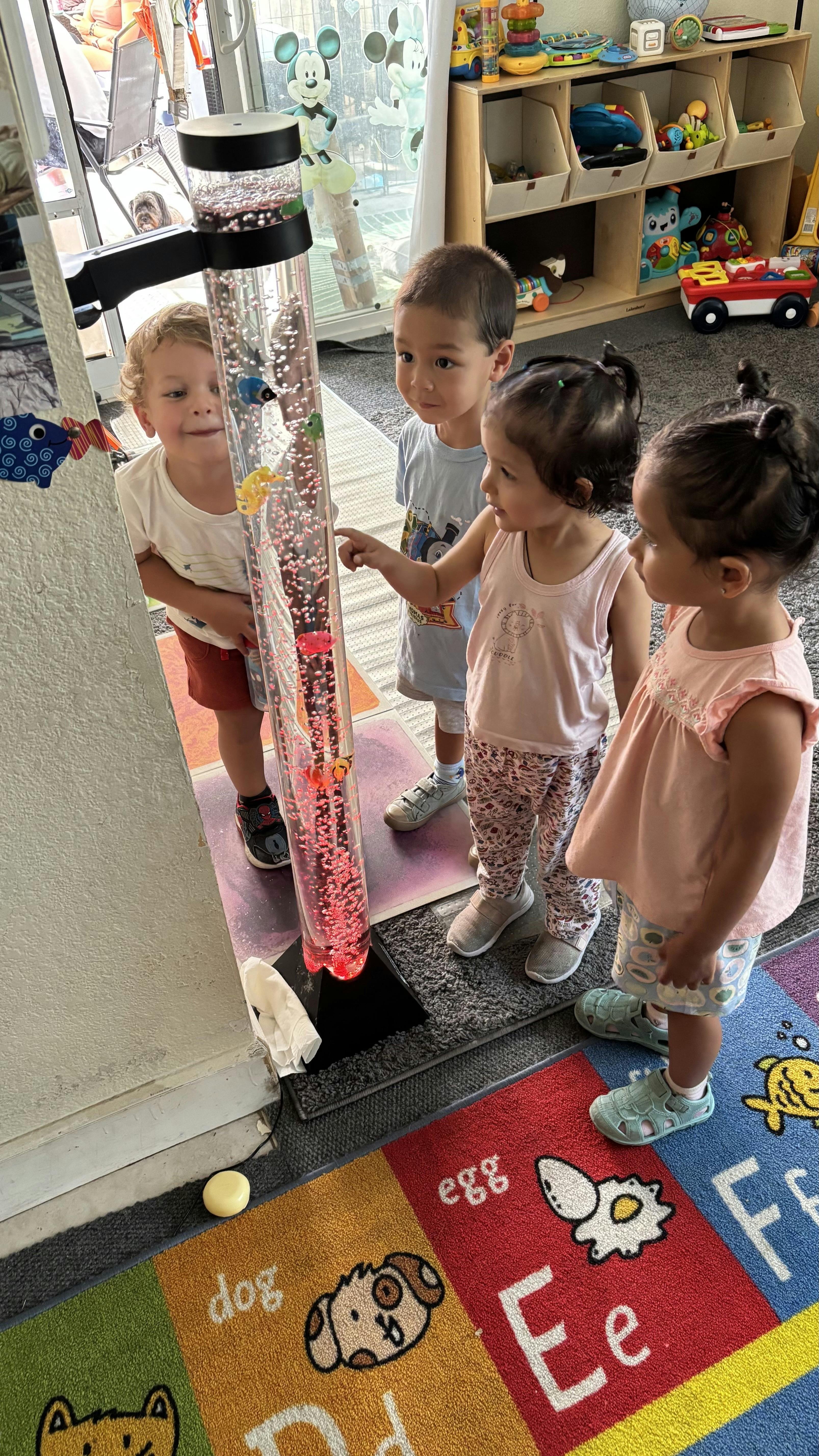 Three children looking at a sensory tube with floating objects