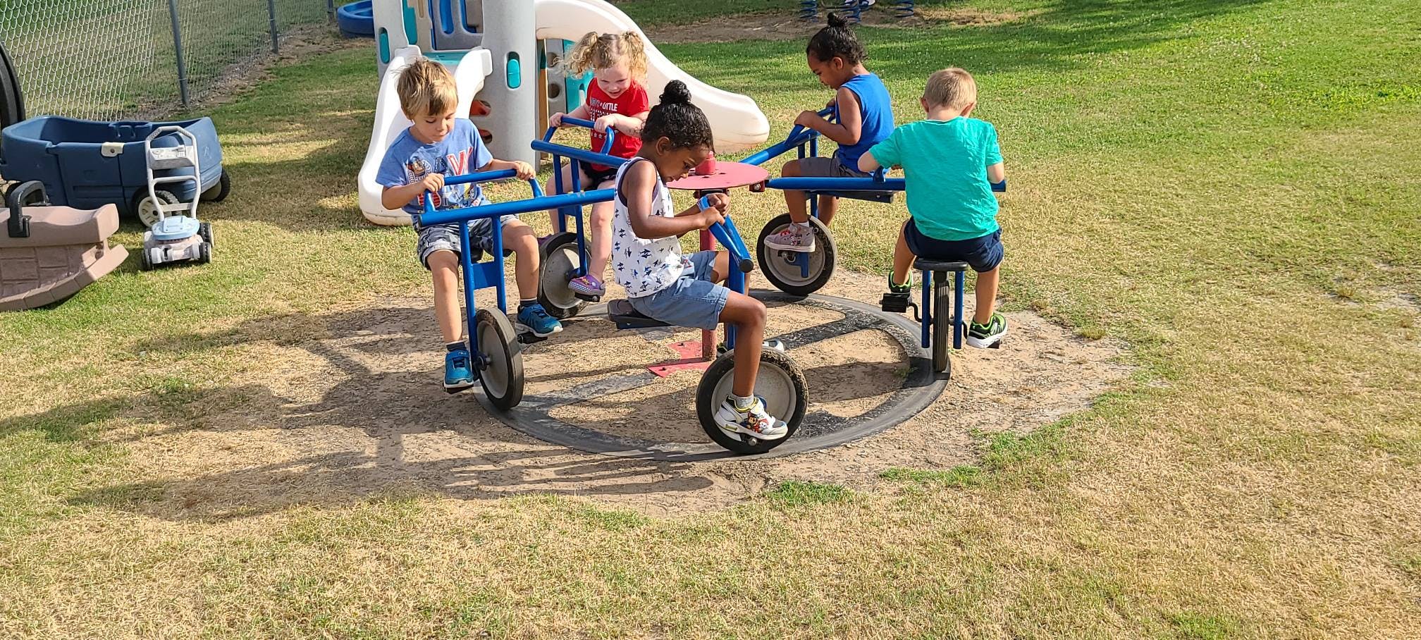 Children on a playground merry-go-round with attached bikes