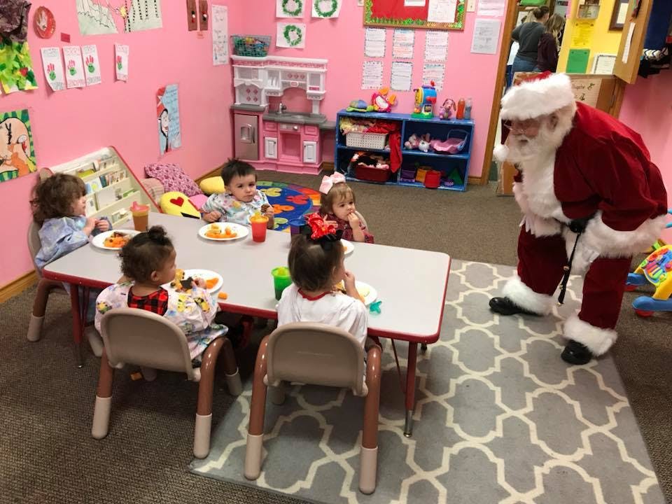 Person in Santa costume interacting with children at a table
