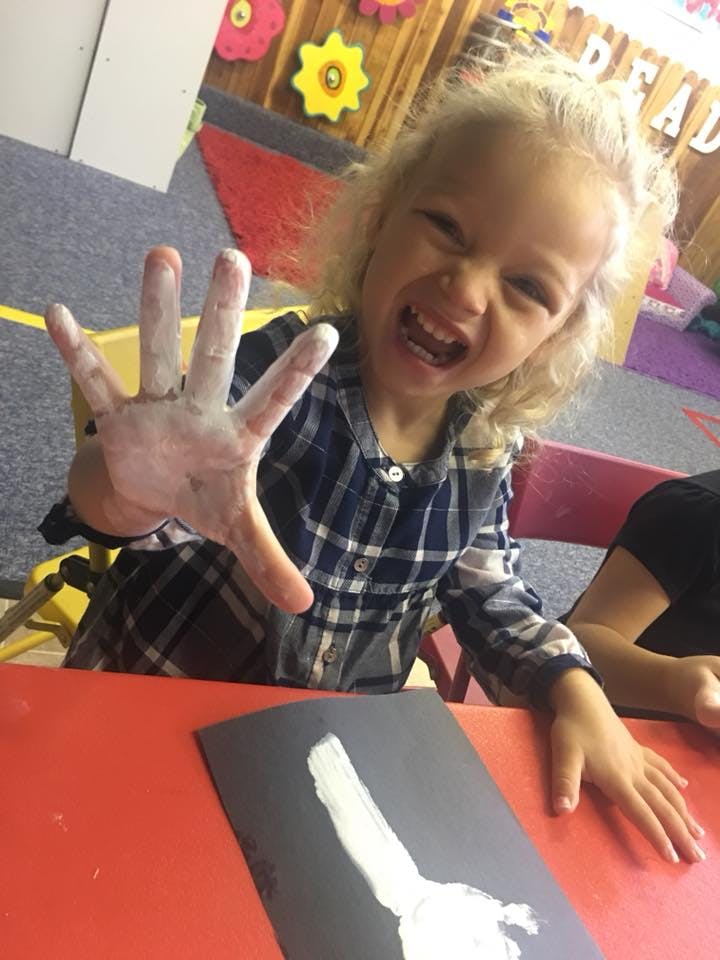 Child with paint on hand, holding it up